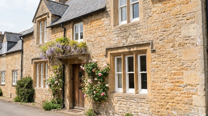 Aluminium Window Surrounds: The Complete UK Guide to Types, Design and Installation in 2026 4 A traditional UK country cottage built from coursed limestone with period window surrounds. The surrounds are carved from matching pale limestone with a simple chamfered profile, forming a raised frame around double-hung sash windows with deep reveals. Climbing plants are visible on the adjacent wall.