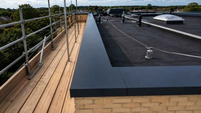Parapet Wall Coping: The Complete UK Guide to Materials, Types, Installation and Specification 10 Flat roof installation showing dark parapet wall coping with scaffolding and rooftop details