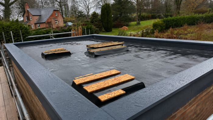 Aluminium Coping Prices: What Affects the Cost of Parapet Wall Coping 5 Aluminium coping prices for a wide flat roof installation with dark grey coping, roof openings and scaffold access on a UK project.