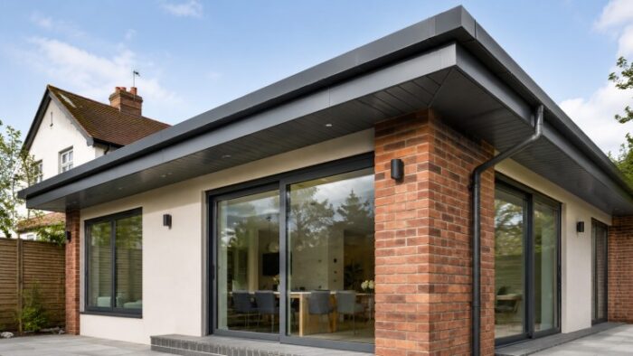 Fascia Boards and Soffits: A Practical UK Roofline Guide 4 Close-up fascia boards and soffits detail showing gutter brackets, black guttering and a downpipe on a UK brick house