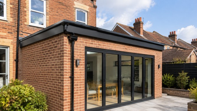 Roof Accessories: A Practical Guide for UK Roof Projects 4 Roof accessories on a new UK brick rear extension with dark aluminium roof edge trim, black guttering