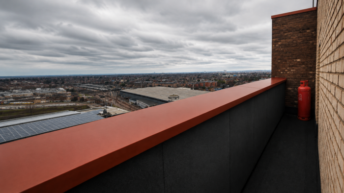 Aluminium Coping Detail: A Practical UK Guide to Wall Tops and Roof Edges 5 Aluminium coping detail on a modern UK roofline with red coping, solar panels and a clean parapet edge.