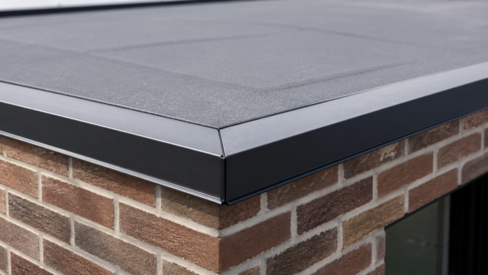 Flat Roof Drip Edge Trim: A Complete UK Guide to Roof Perimeter Details 4 Close-up flat roof drip edge trim detail on a brick roof corner with neatly finished dark metal edging.