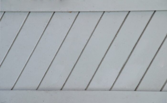 Contractor fastening aluminium fascia board on a roof edge with a power drill.