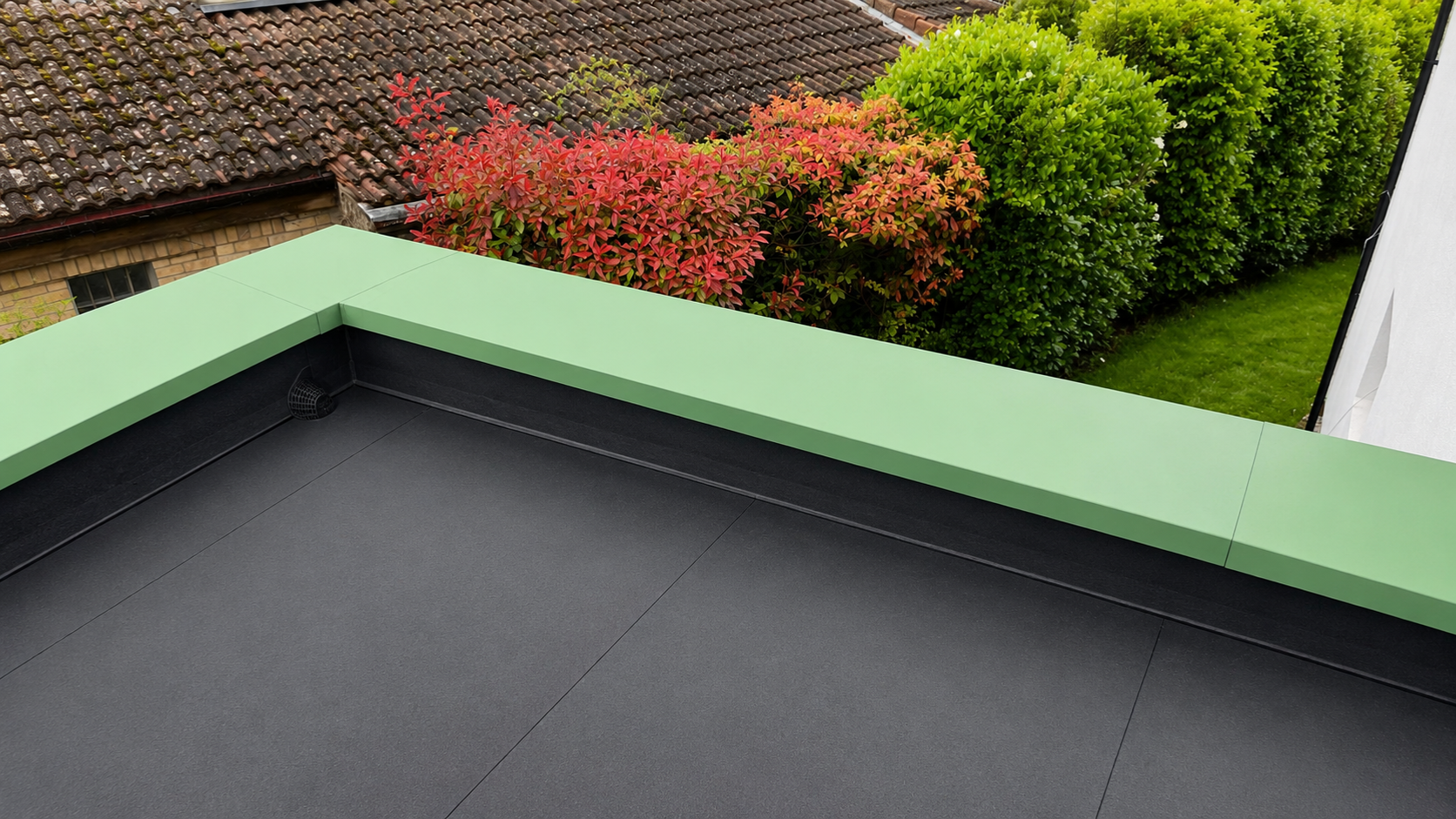 Green aluminium coping installation around a clean black flat roof on a UK residential property
